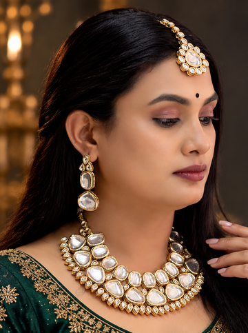 Model wearing a Kundan-style bridal necklace set with matching earrings and maang tikka by JANAKSH