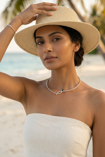 Beach jewellery editorial with a stylish pose and sun hat, highlighting the necklace
